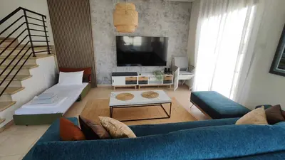 a living room with a blue couch and a tv at My Mythical Pearl in Protaras