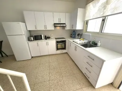 a kitchen with white cabinets and a sink and a window at Mattis Seafront Beachhouse in Pervolia