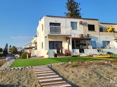 a white house with a porch and a yard at Mattis Seafront Beachhouse in Pervolia