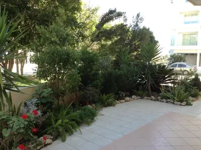 a garden with plants and flowers on a sidewalk at St. Lazaros Seaside Apartment in Larnaka