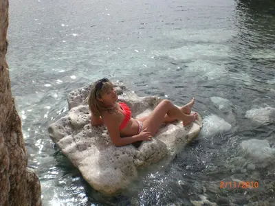 a young girl sitting on a rock in the water at St. Lazaros Seaside Apartment in Larnaka
