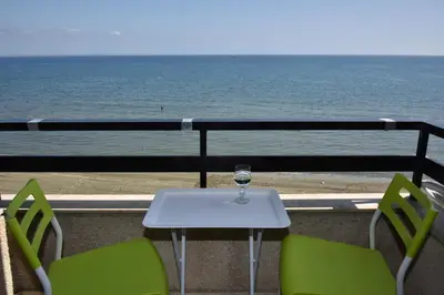 a table and chairs with a glass of wine on a balcony at Stadem Studios in Larnaka