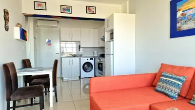 a living room with a red couch and a kitchen at Cyprus Dreams Village in Protaras