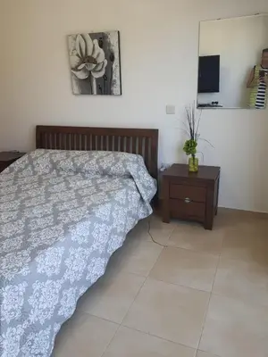 a bedroom with a bed and a table with a flower on the wall at Yama's Villa - Polyxenia luxury, protaras, cyprus in Protaras