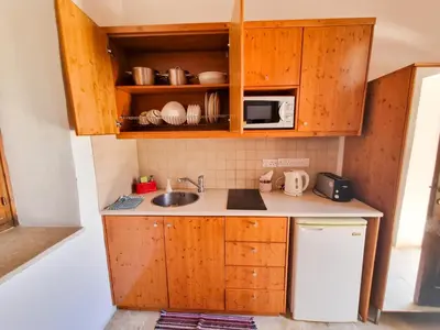 a small kitchen with wooden cabinets and a sink at Skarinou Village Poolside Escape Studio with Pool facilities in Skarinou