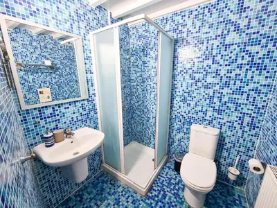 a blue tiled bathroom with a toilet and a sink at Traditional Village Pool Paradise Family Apartment in Skarinou