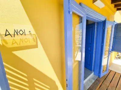 a blue door on the side of a yellow building at Village Charm with Pool Apartment at Skarinou in Skarinou