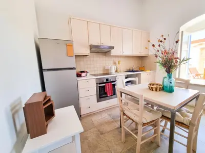 a kitchen with a table and a white refrigerator at Village Charm with Pool Apartment at Skarinou in Skarinou