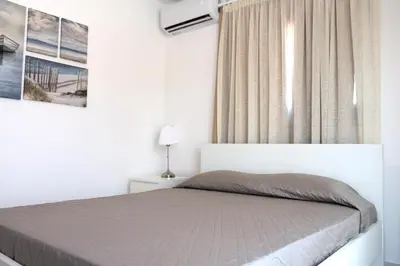 a white bedroom with a bed and a window at Musan Boutique Apartments in Ayia Napa