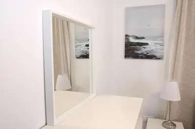 a mirror in a white room with a lamp at Musan Boutique Apartments in Ayia Napa