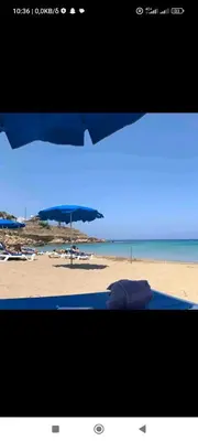 a view of a beach with an umbrella and chairs at Vicky apartment in Paralimni