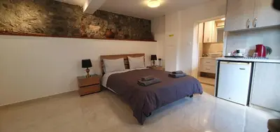 a bedroom with a bed and a small kitchen at Chic Elegance Meets Village Gem in Pelendri