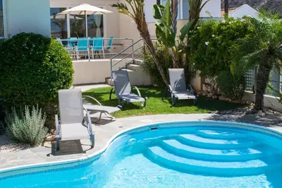 a swimming pool with two chairs and an umbrella at Anastasia in Pissouri