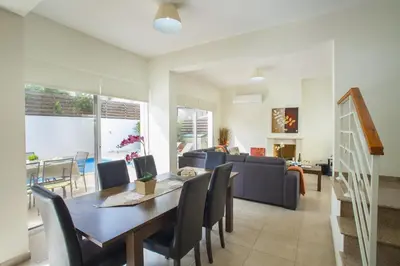 a dining room and living room with a table and chairs at Villa Cliantha in Protaras