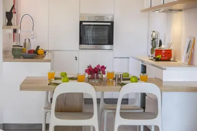 a kitchen with a wooden table and white chairs at Liora Suite in Protaras