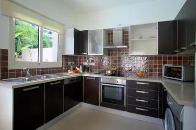 a kitchen with brown cabinets and a sink and a window at Michelle 8 in Protaras