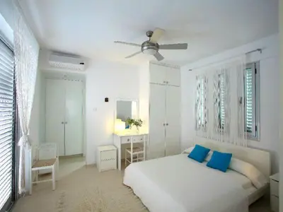 a white bedroom with a bed with blue pillows at Architect's Villa in Protaras