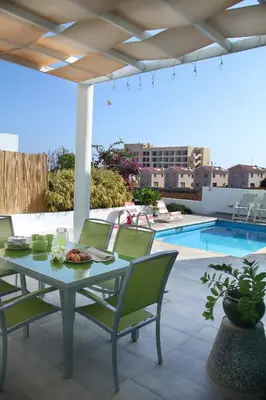 a table and chairs on a patio with a pool at Architect's Villa in Protaras