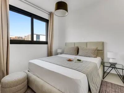 a white bedroom with a large bed and a window at Sanders Triple in Limassol