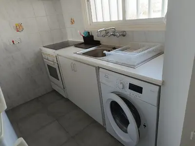 a kitchen with a sink and a washing machine at Julie's beach house in Voroklini