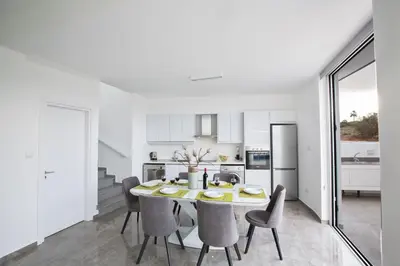 a white kitchen and dining room with a table and chairs at Villa Prol24,brand New 2bdr Protaras Villa with Pool,close to Fig Tree Bay Beach in Protaras