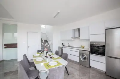 a white kitchen with a table and chairs in it at Villa Prol24,brand New 2bdr Protaras Villa with Pool,close to Fig Tree Bay Beach in Protaras