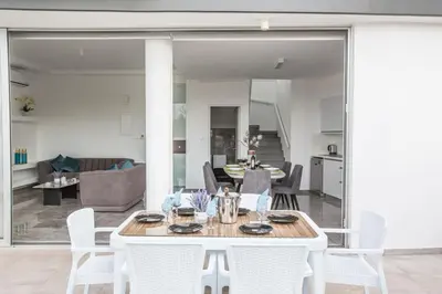 a dining room and living room with a table and chairs at Villa Prol24,brand New 2bdr Protaras Villa with Pool,close to Fig Tree Bay Beach in Protaras