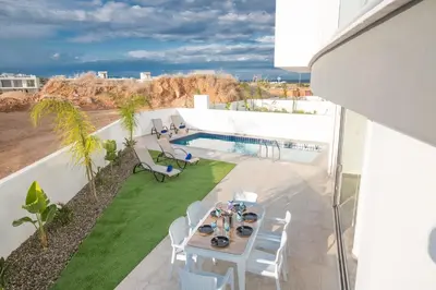 a balcony with a table and chairs and a swimming pool at Villa Prol24,brand New 2bdr Protaras Villa with Pool,close to Fig Tree Bay Beach in Protaras