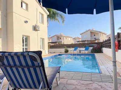 a chair and an umbrella next to a swimming pool at Sunset Pearl Holiday Villa in Ayia Napa