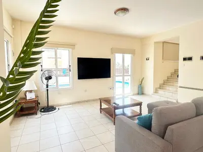 a living room with a couch and a flat screen tv at Sunset Pearl Holiday Villa in Ayia Napa