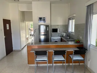 a kitchen with a counter and some chairs in it at Themis Beach Apartments in Larnaka