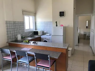 a kitchen with a counter with chairs and a refrigerator at Themis Beach Apartments in Larnaka