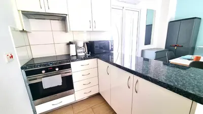 a kitchen with white cabinets and a black counter top at Dream Escape Apt 1 - 6 min walk to Kastella Beach! in Larnaka