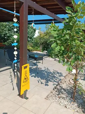 a yellow warning sign on a patio with a tree at Ferienhaus_FamilyKrausz in Pervolia