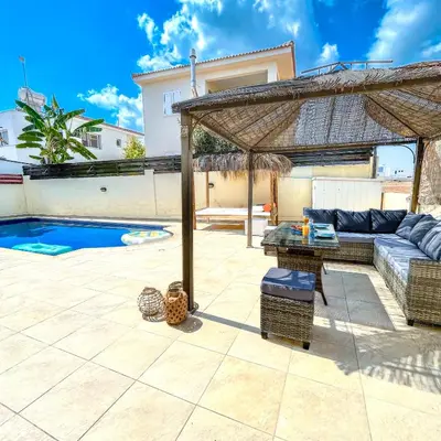 a patio with a couch under a pavilion next to a pool at Mediterranean Breeze Villa in Protaras