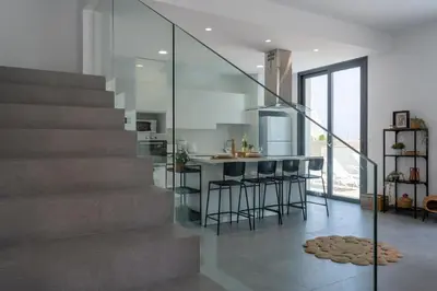 a kitchen with a staircase and a bar with stools at Villa Flora's 3-BR Retreat & Private Pool in Protaras in Paralimni