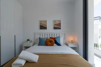 a bedroom with a bed with pillows and a window at Villa Flora's 3-BR Retreat & Private Pool in Protaras in Paralimni