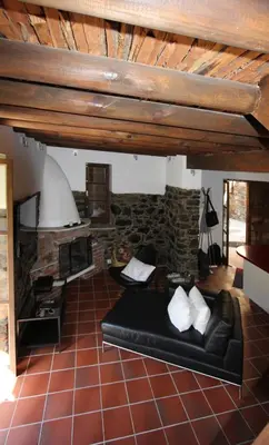 a living room with a black couch and a stone fireplace at River House in Kakopetria