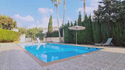 a swimming pool with an umbrella in a yard at Nissi 86 Apartment - Luxcyservices in Ayia Napa