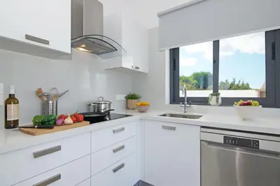 a white kitchen with white cabinets and a sink at Villa Celestia in Protaras