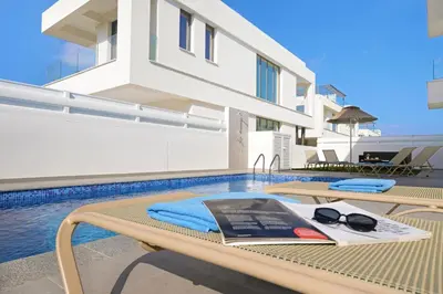 a book and sunglasses on a table next to a swimming pool at Villa Celestia in Protaras
