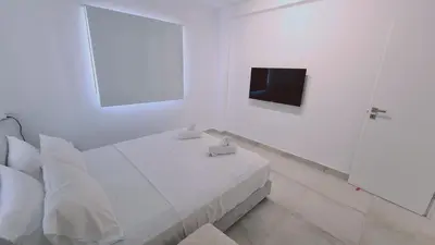 a white bedroom with a bed and a tv at STAY Napa Aura Apartment in Ayia Napa