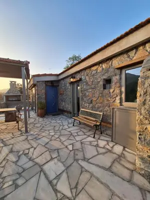 a stone patio with a bench next to a building at Jennas House in Arakapas