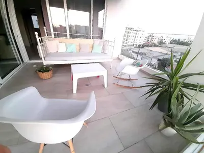 a balcony with a couch and a chair and a table at Happy Tucan in Larnaka