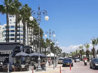 a street with cars driving down a street with palm trees at Happy Tucan in Larnaka