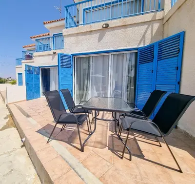 a patio with a table and chairs in front of a building at Beach Vibes Beachfront Apartment in Pyla
