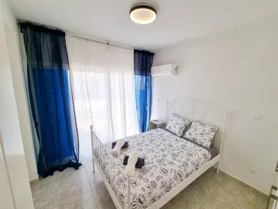 a bedroom with a white bed with blue curtains at Beach Vibes Beachfront Apartment in Pyla