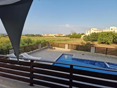 a swimming pool with two chairs and a fence at Kalifi Pool Apartment in Paralimni