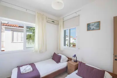 a bedroom with two beds and two windows at Villa Armostia in Protaras