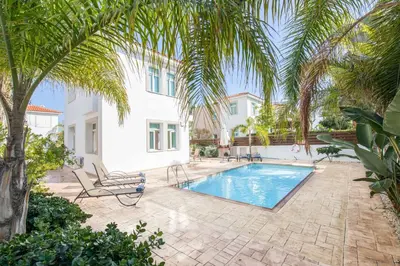 a villa with a swimming pool and palm trees at Villa Armostia in Protaras